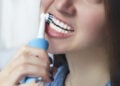 Close up of brushing teeth with electric toothbrush. Young woman